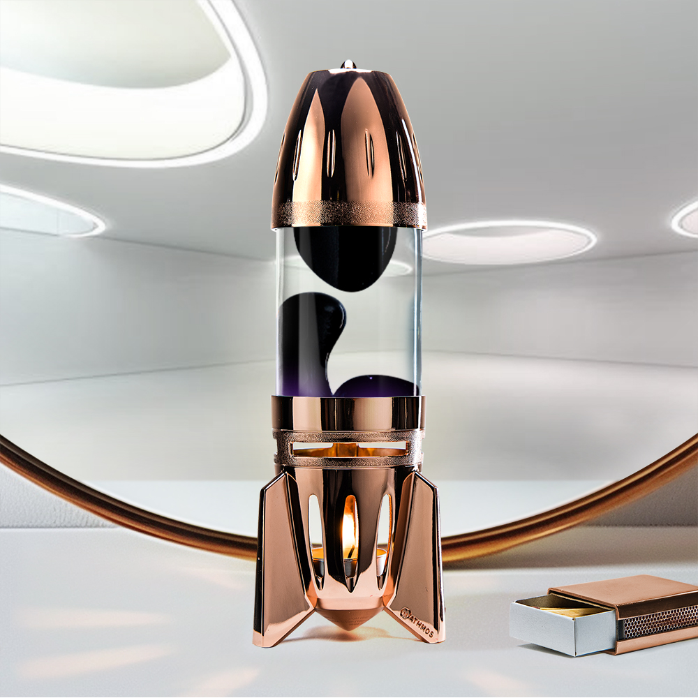 Varinė raketos formos Mathmos Fireflow žvakinė lavos lempa su skaidriu skysčiu ir juoda lava šviesiame fone su degtukų dėžute