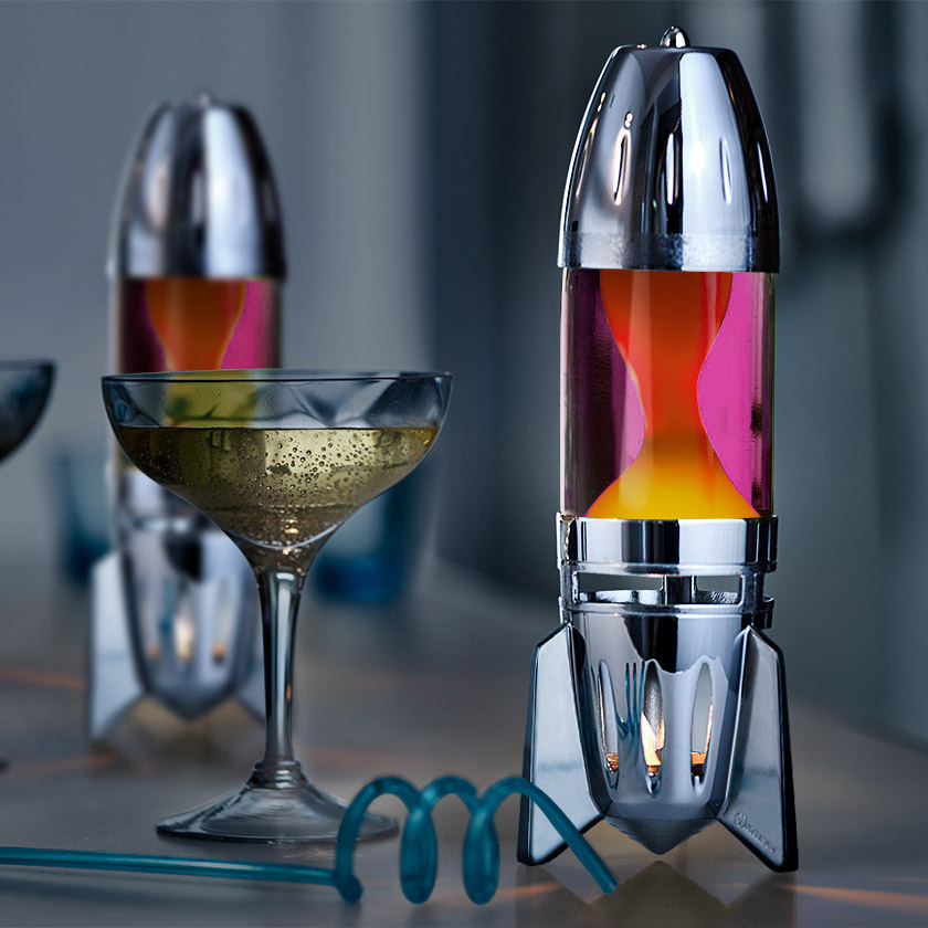 Mathmos Fireflow žvakinė lavos lempa su sidabriniu korpusu, rausvu skysčiu ir geltona lava, moderni interjero detalė ant stalo